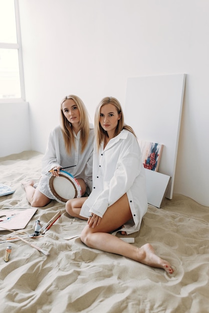 Portrait of happy twin girls artists Sister girls in a photo studio on the sand