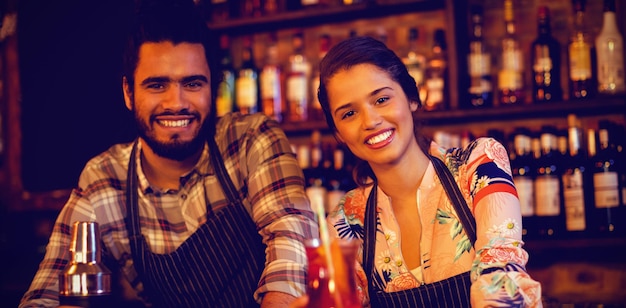 Portrait of happy waiter and waitress standing at counter