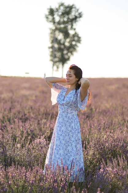 Portrait of a happy woman in a blue dress enjoying a sunny summer day in a lavender field Fresh air Lifestyle