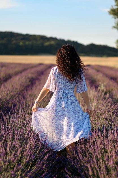 Portrait of a happy woman in a blue dress enjoying a sunny summer day in a lavender field Fresh air Lifestyle