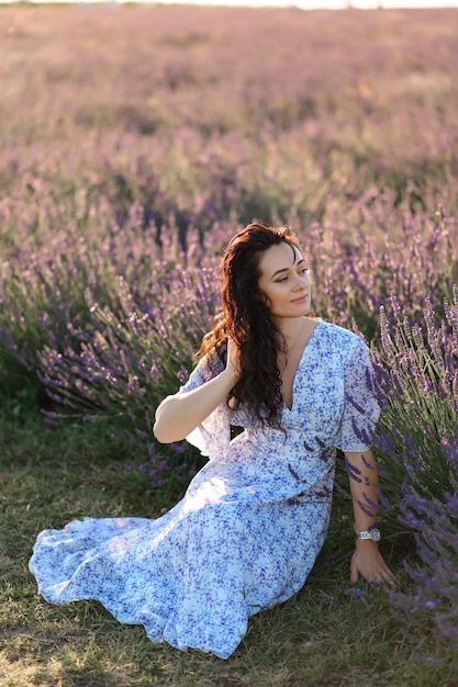 Portrait of a happy woman in a blue dress enjoying a sunny summer day in a lavender field Fresh air Lifestyle