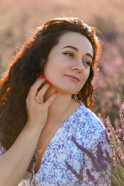 Portrait of a happy woman in a blue dress enjoying a sunny summer day in a lavender field Fresh air Lifestyle