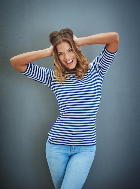 Portrait happy woman and excited in studio backdrop as confident in trendy fashion or style Female person outfit and fun for cool casual and aesthetic with isolated clothes and gray background