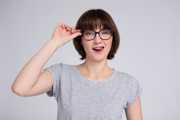 Portrait of happy woman in eyeglasses with braces on teeth over gray background