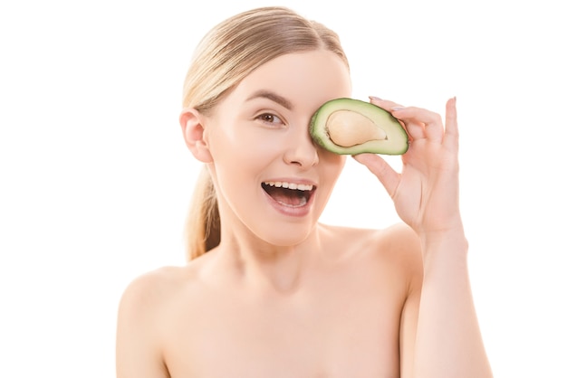 The portrait of the happy woman with an avocado on the white background