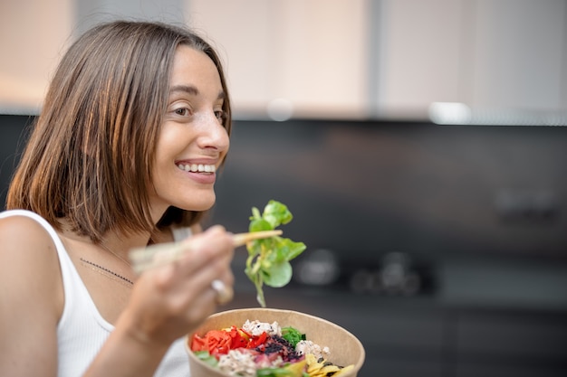 Portrait of a happy woman with healthy bowl at kitchen