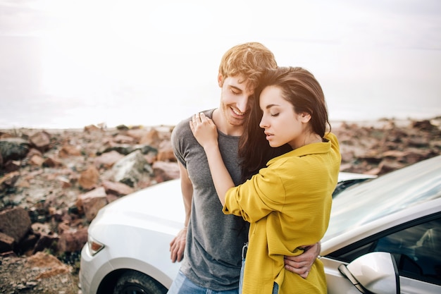 Portrait of a happy young adult couple near the sea on a road trip.