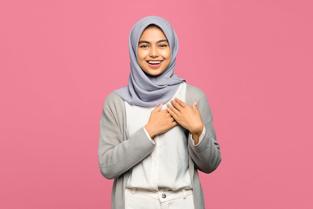 Portrait of happy young Asian woman keeps hands on chest near heart