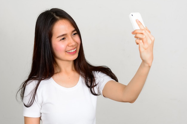 Portrait of happy young beautiful Asian woman