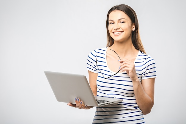 Portrait of happy young beautiful surprised woman with glasses standing with laptop