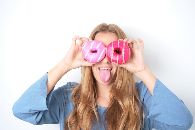 Portrait of happy Young blonde woman showing multicolored donuts