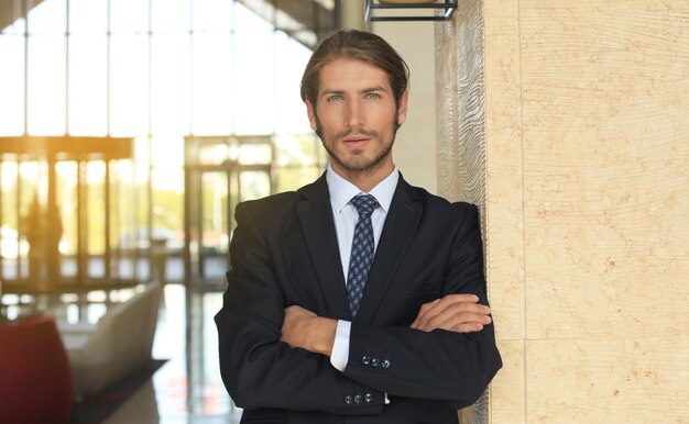 Portrait of happy young businessman standing in hotel lobby.