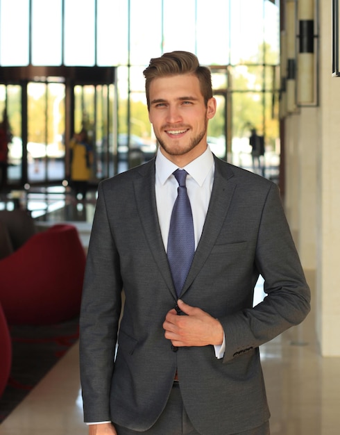 Portrait of happy young businessman standing in hotel lobby.