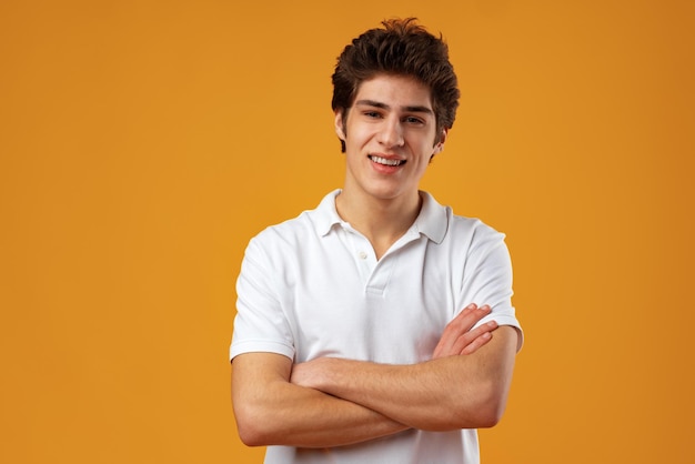 Portrait of a happy young casual man standing over yellow background