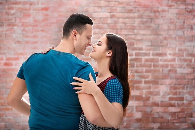 Portrait of happy young couple against brick wall