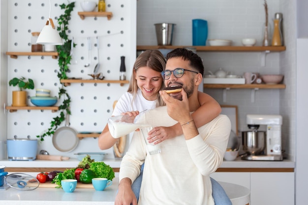 Portrait of happy young couple cooking together in the kitchen at home Cute young couple enjoying their breakfast together she is pouring him milk