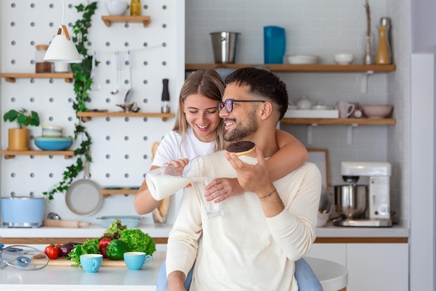 Portrait of happy young couple cooking together in the kitchen at home Cute young couple enjoying their breakfast together she is pouring him milk