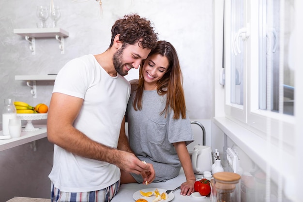 Portrait of happy young couple cooking together in the kitchen at home. romantic Attractive young woman and handsome man are enjoying spending time together while standing on light modern kitchen.