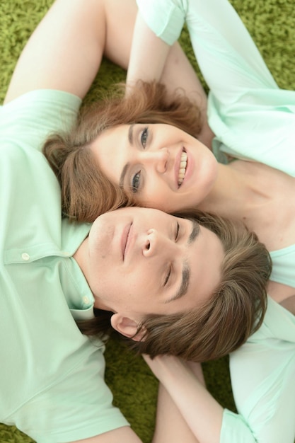 Portrait of happy young couple in love lying on floor at home