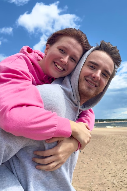 Portrait of happy young couple walk on the beach love hug each other guy is carrying his girlfriend