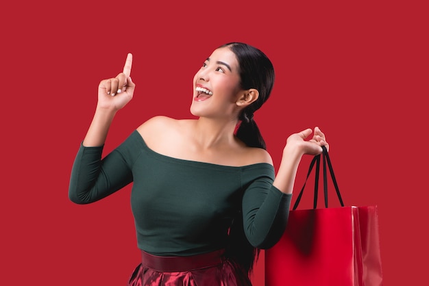 portrait of happy young cute woman posing with shopping bags over Red background.