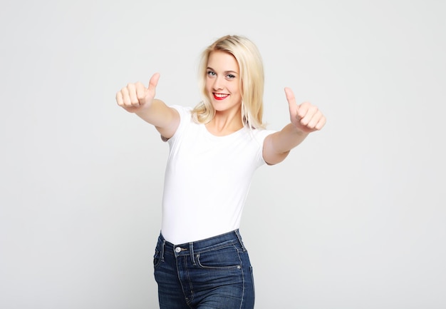 Portrait of a happy young girl showing ok gesture and winking studio shoot