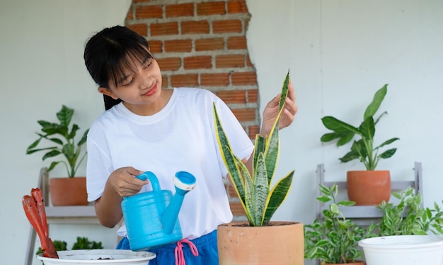 Portrait happy young girl watering green plants at home Asian girl