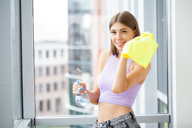 Portrait Of Happy Young Maid Cleaning Glass With Sponge