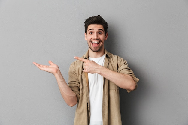 Portrait of a happy young man pointing at copy space