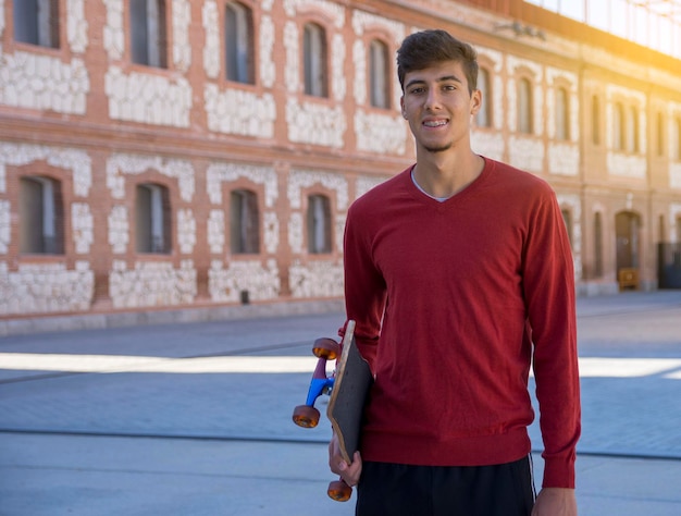 Portrait of happy young man with skateboard. Young fashion man with skateboard outdoors.