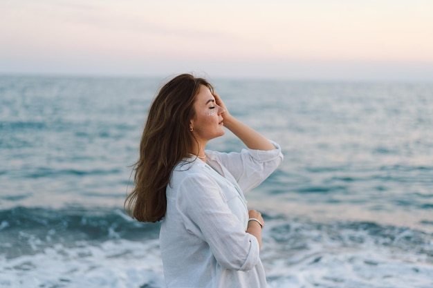 Portrait of a happy young woman on a background of beautiful sea The girl looks at the magical sea Freedom and happiness