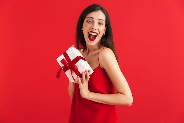 Portrait of a happy young woman in dress holding present box isolated