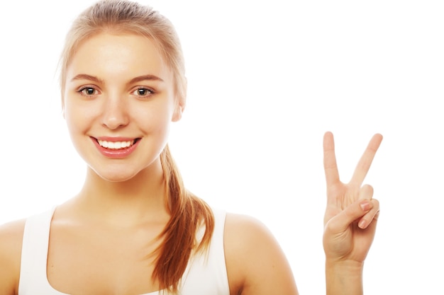 Portrait of happy young woman giving peace sign isolated on white background