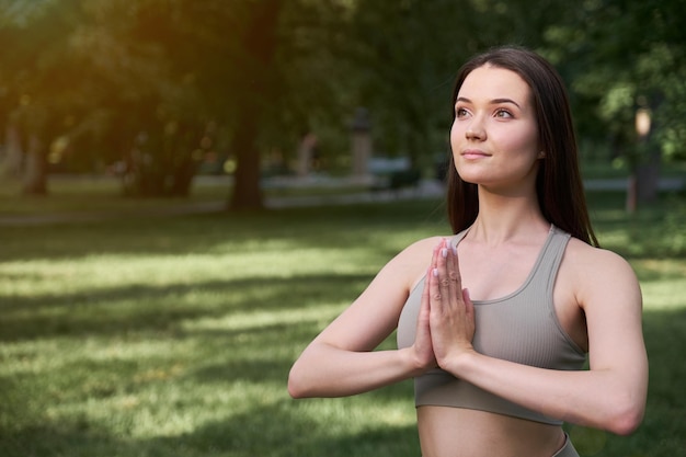 Portrait of a happy young woman practicing yoga in the park on a summer day