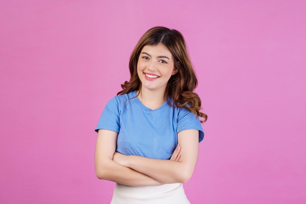 Portrait of happy young woman wearing casual tshirt crossed arms isolated over pink background