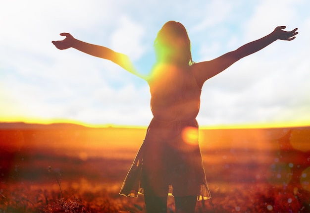 Portrait of happy young woman with arms outstretched on nature background