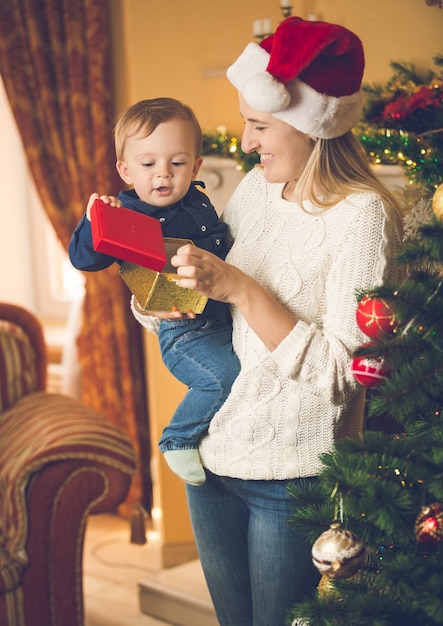 Portrait of happy young woman with her baby son at Chrsitmas tree