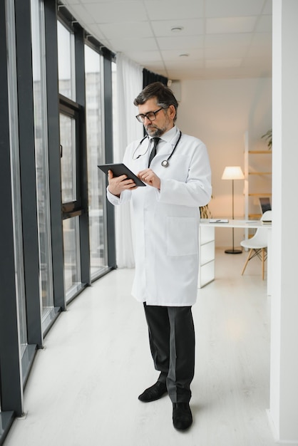 Portrait of healthcare worker Image of senior male doctor wearing lab coat and standing at private clinic