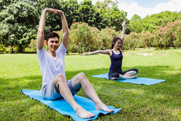 Portrait healthy couples sport practice yoga outdoors together in the courtyard shady garden.