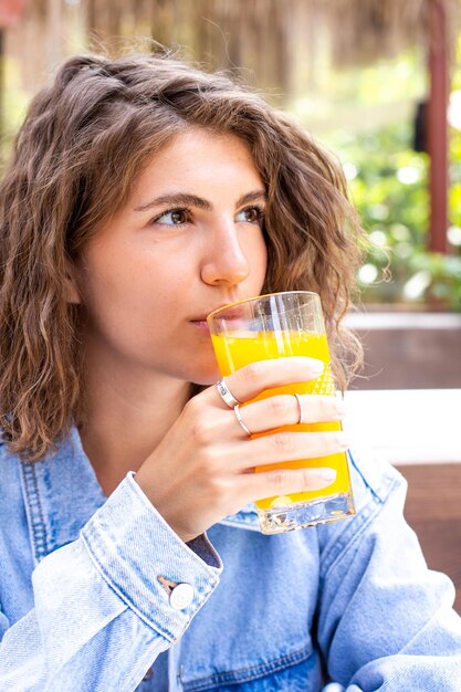 Portrait of a healthy young brunette beauty with glass of orange juice and fruit