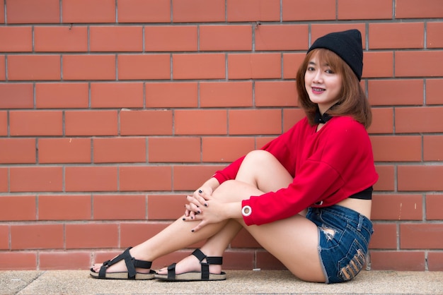 Portrait of hipster girl  on brick wall background,Beautiful asian woman pose for take a photo,Kawai