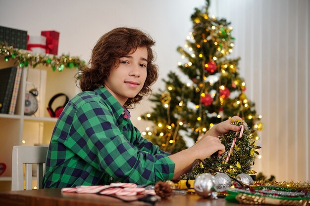 Portrait of Hispanic teenage boy making decoration for Christmas tree at home