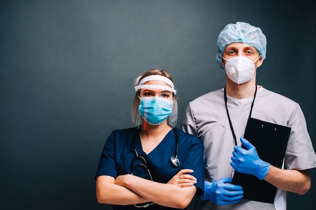 Portrait of hospital workers nurses colleagues in medical protective masks isolated on dark background.