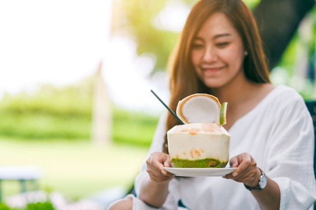 Portrait image of a beautiful asian woman holding and drinking coconut juice in the outdoors