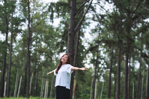 Portrait image of a happy young asian woman with arms opening in the park