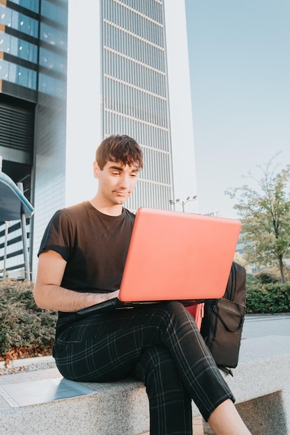 Portrait image of male with short hair using laptop for chatting online with friends and working after the class, master exchange student, connected to free wireless. Handsome man texting messages.