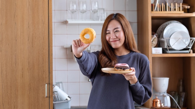 Portrait image of a young asian woman holding and looking through donuts holes in the kitchen at home