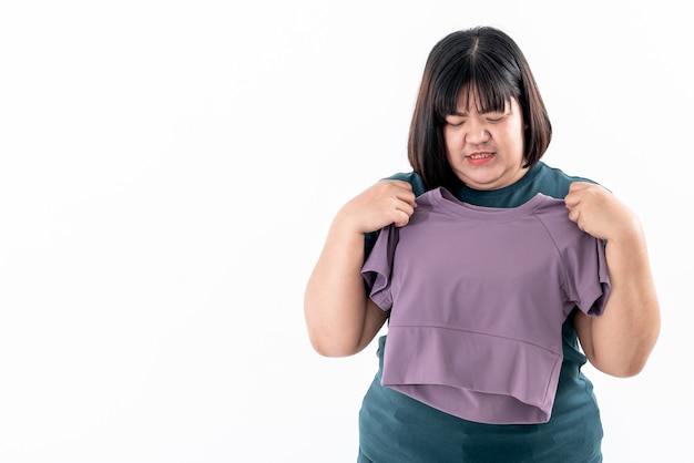 Portrait images of Asain fat woman looking and holding a shirt which is smaller than her body