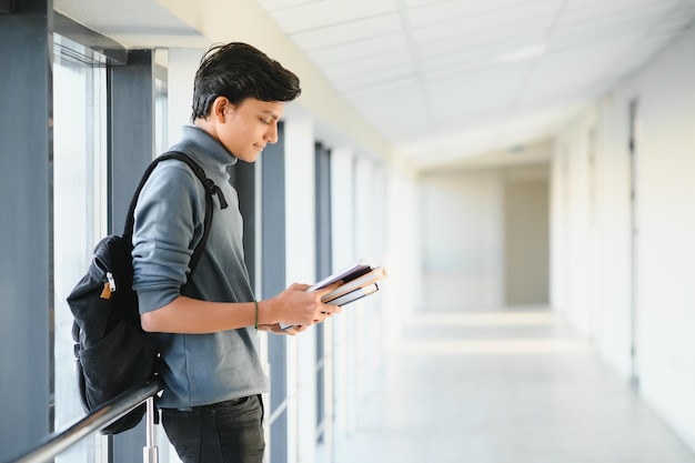 Portrait of indian college boy holding books.