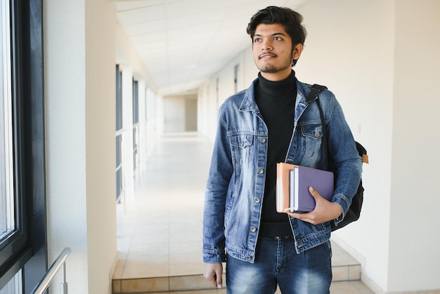 Portrait of indian college boy holding books.